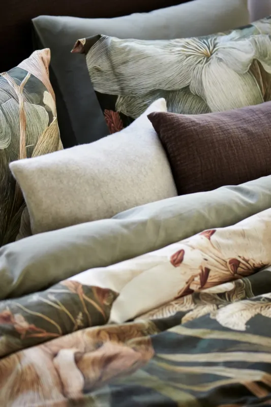 Vandyck grijze kussensloop Home Serina in Stone en donkerbruine kussensloop Pure 68 in Dark Truffle bij dekbedovertrek Floraluxe met rijke bloemenprint en effen groene dekbedovertrek Pure 84 in Thyme